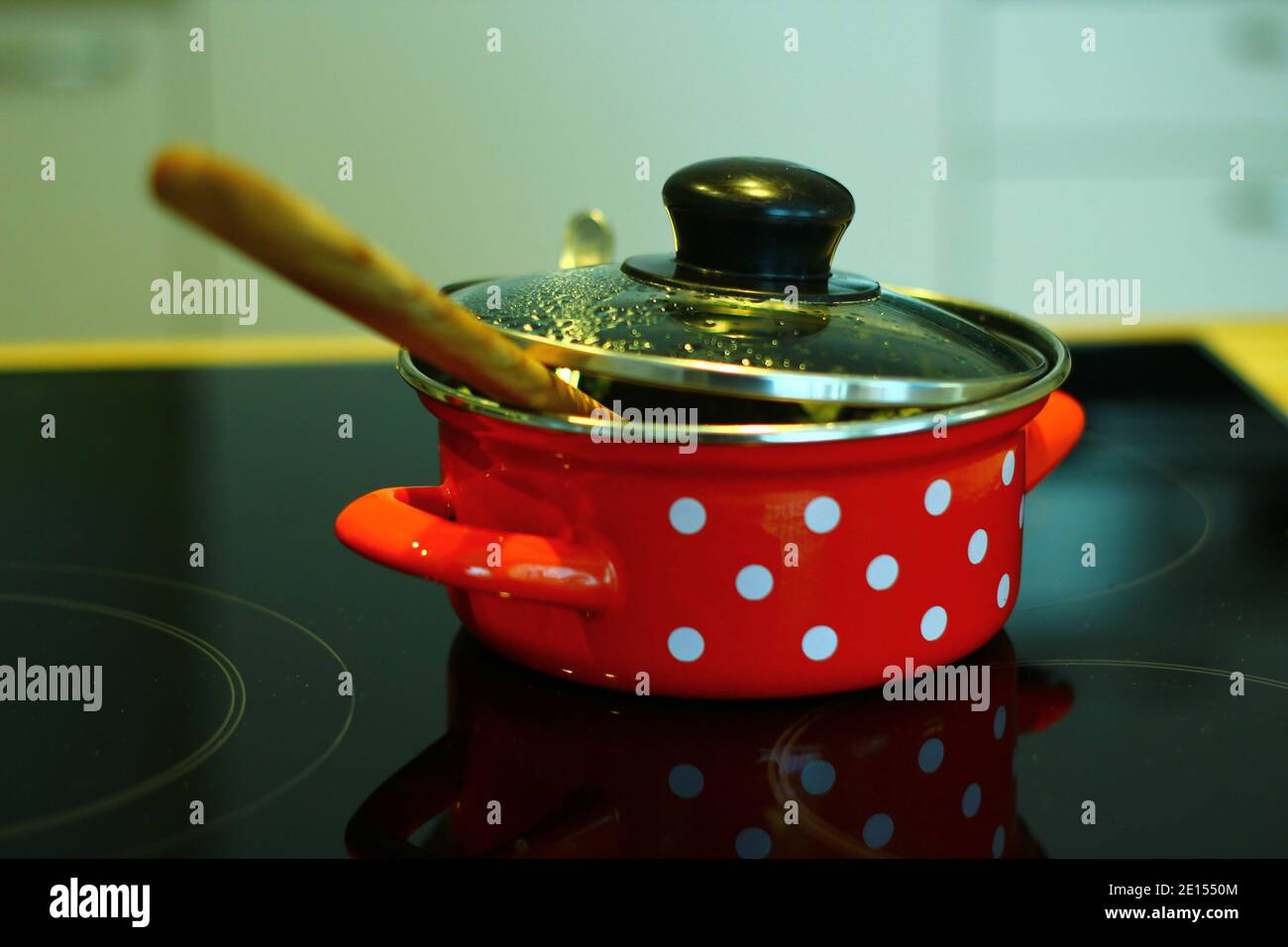 Red Enamel Bowl With White Dots On A Hob Stock Photo