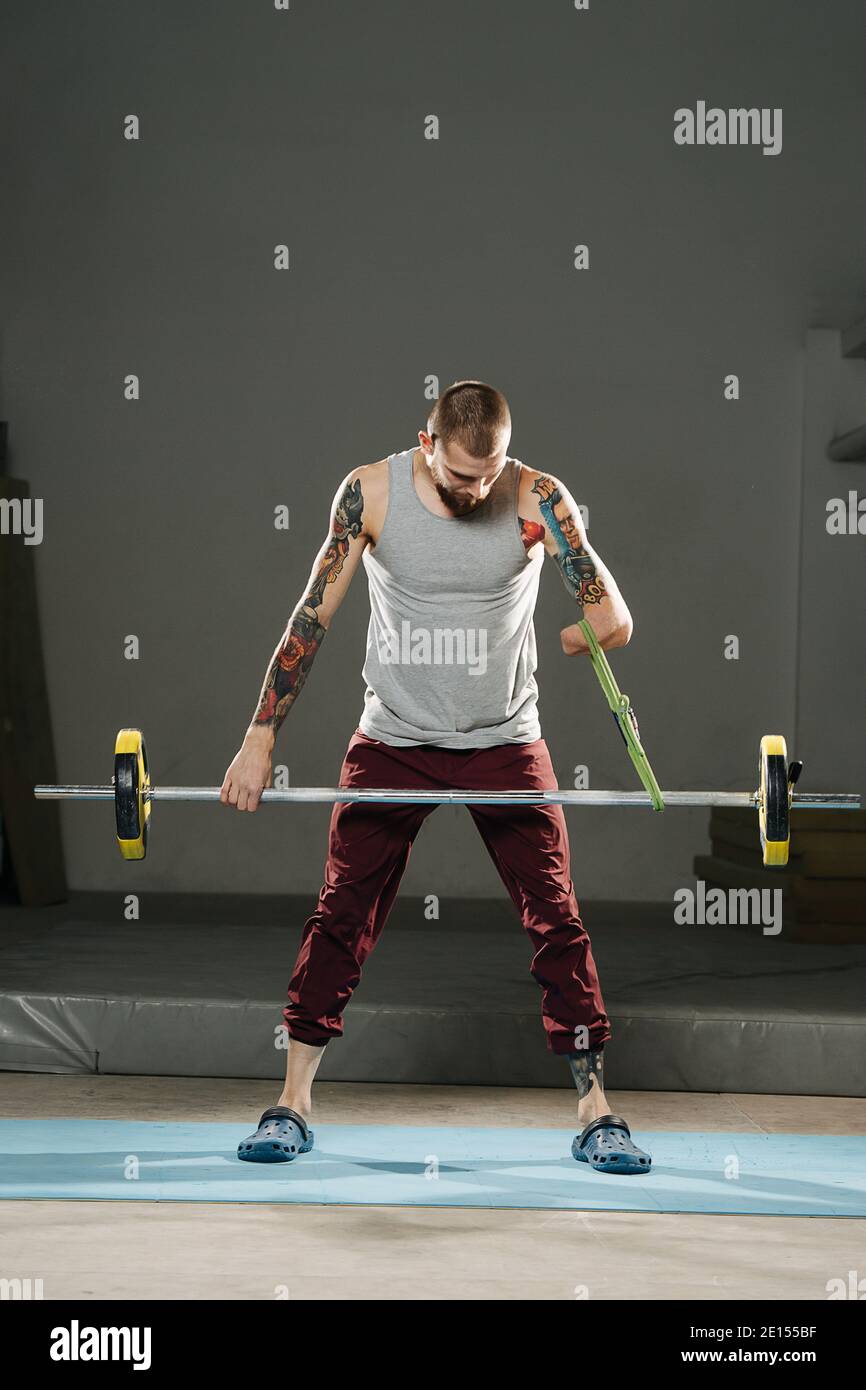 Resolved young disabled armless man training in the gym. Tackling barbell weight Stock Photo