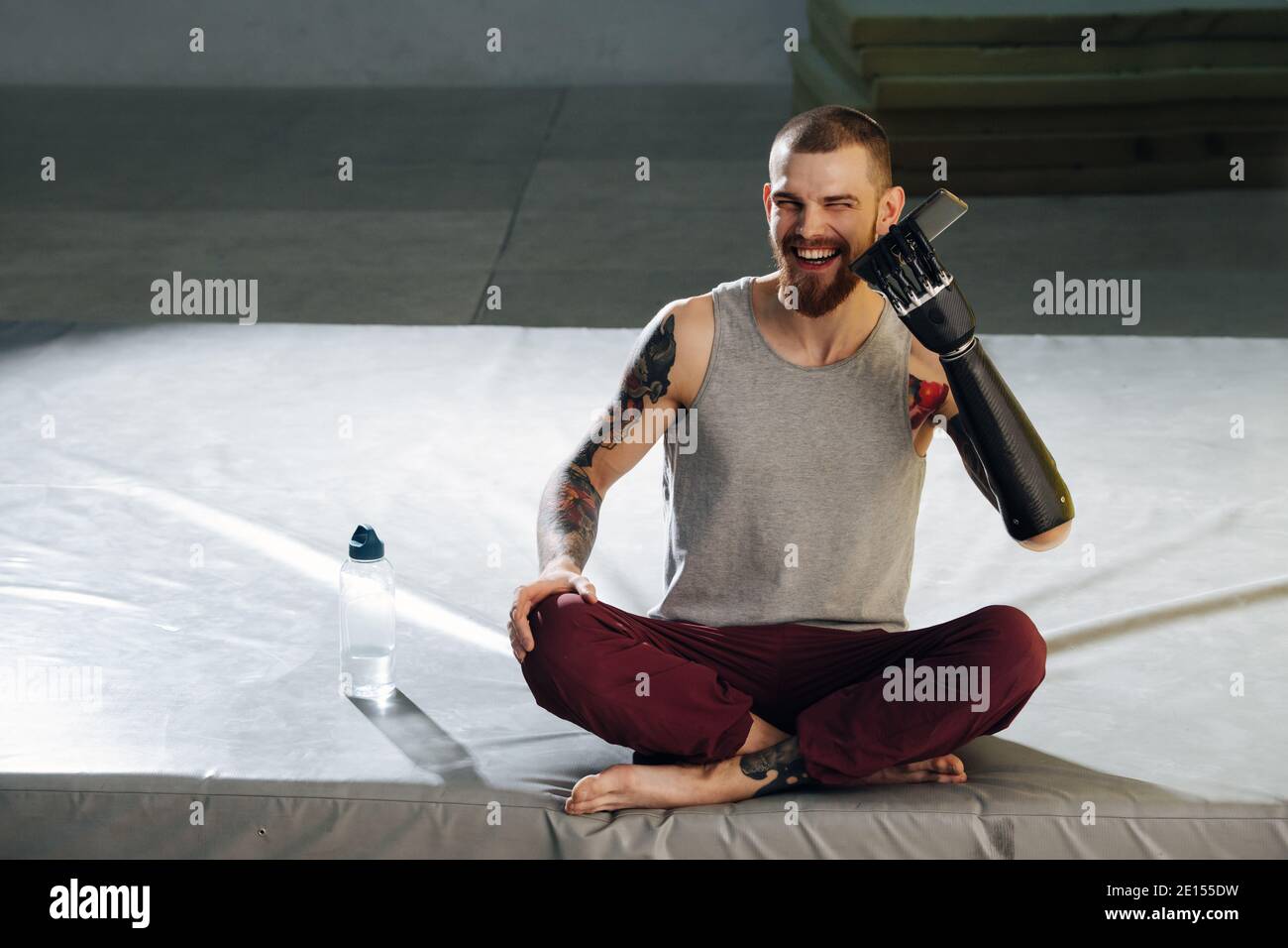 Funny cyborg man trying to hold his phone with bionic hand, laughing Stock Photo