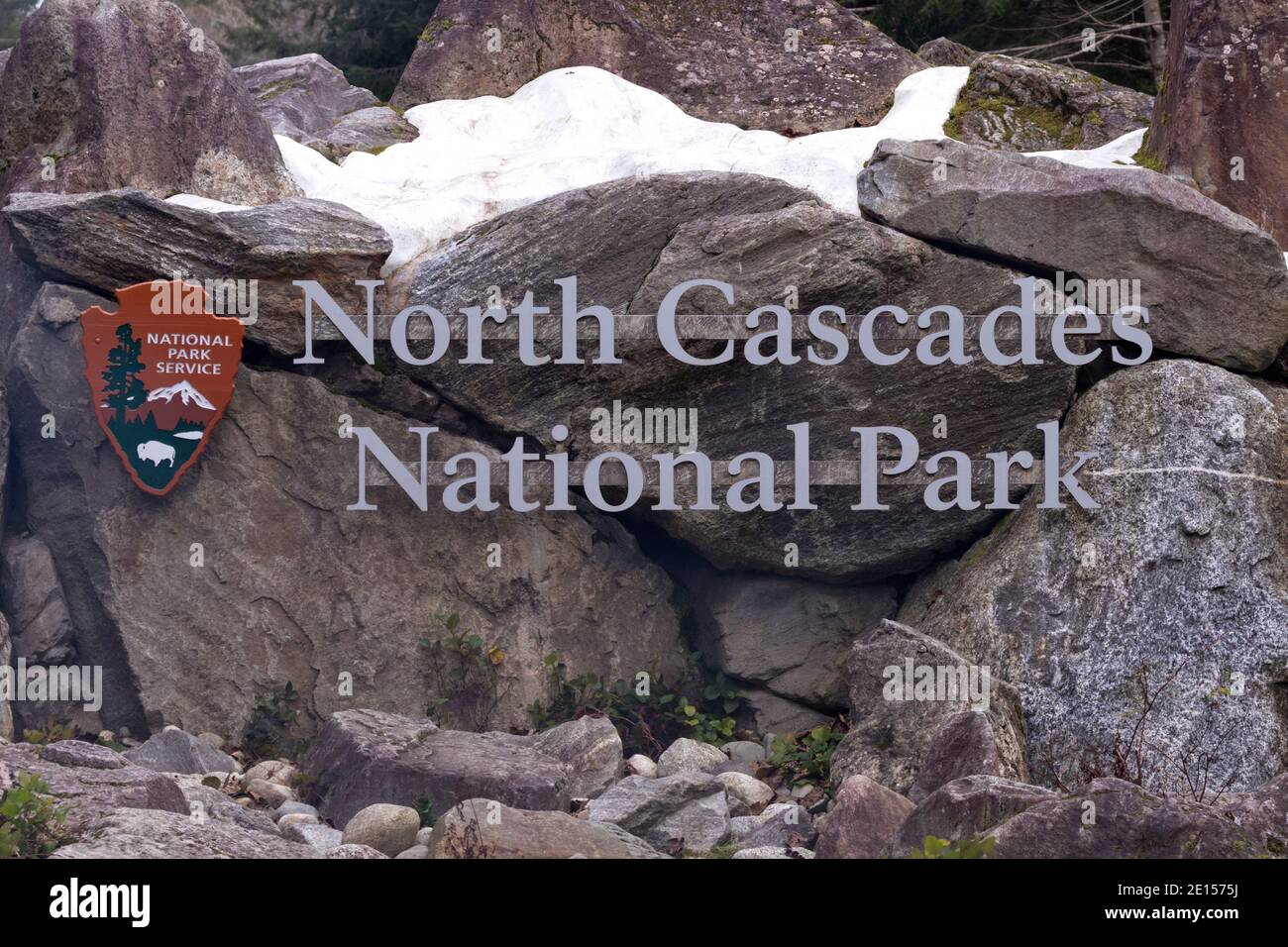 Sign for North Cascades National Park in northern Washington State in the heart of the Cascade Mountain Range. Snow in the rocks and boulders around t Stock Photo