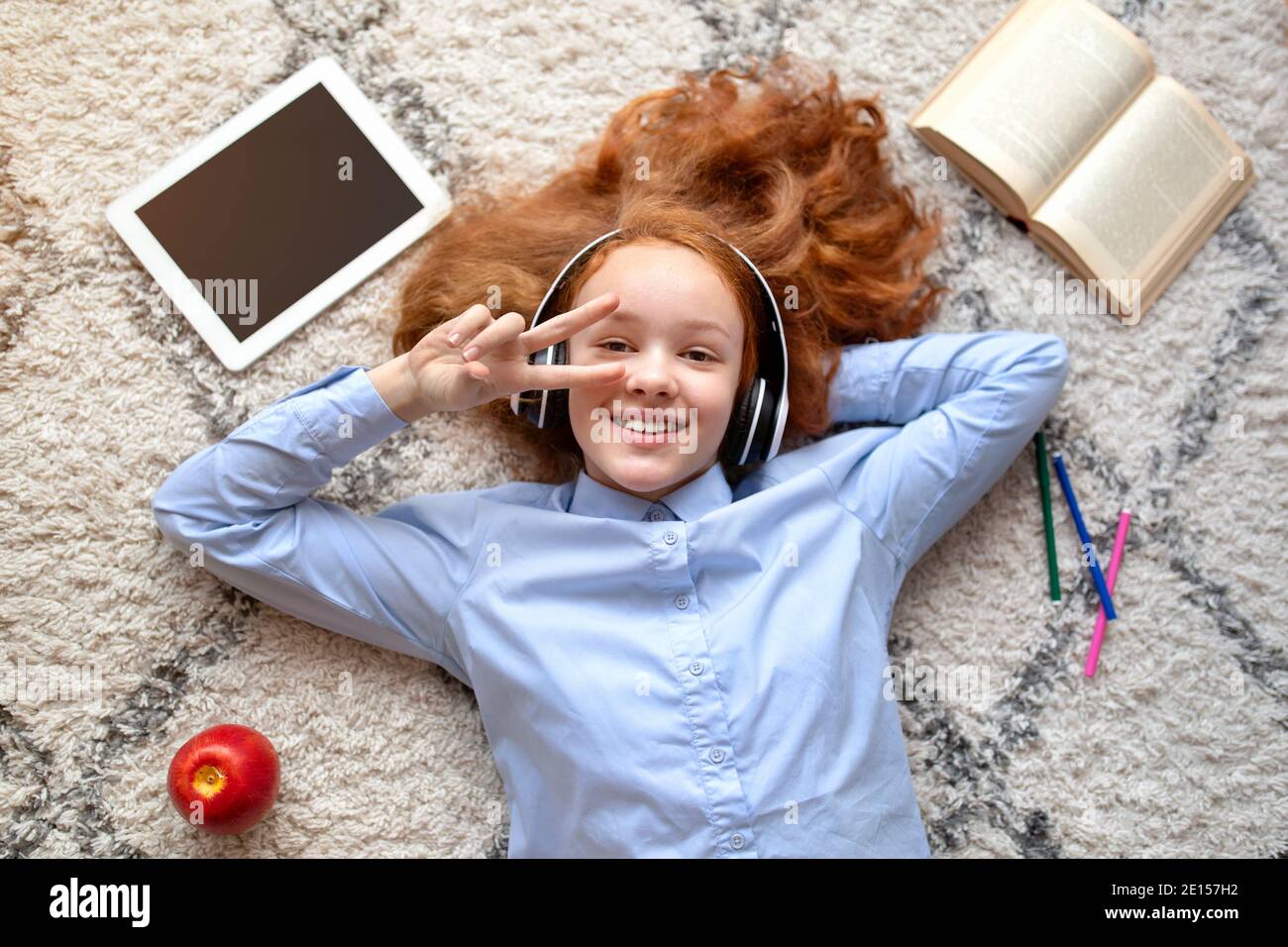 Teenage girl lying on floor carpet, listening to music Stock Photo - Alamy