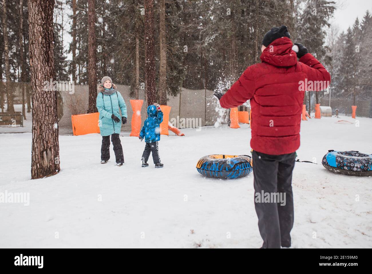 Minsk, Belarus - December 03, 2020: Friendly family playing snowballs in a snowy forest - mom dad and child are having fun on christmas holidays Stock Photo