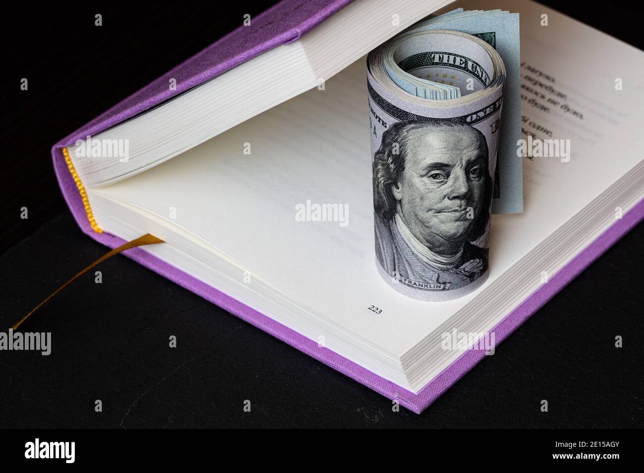 roll of 100 dollar banknotes in violet book Stock Photo