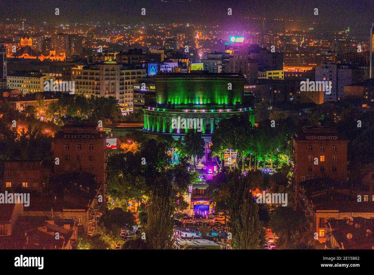 Aerial view of a brightly lit city square and surrounding buildings at ...
