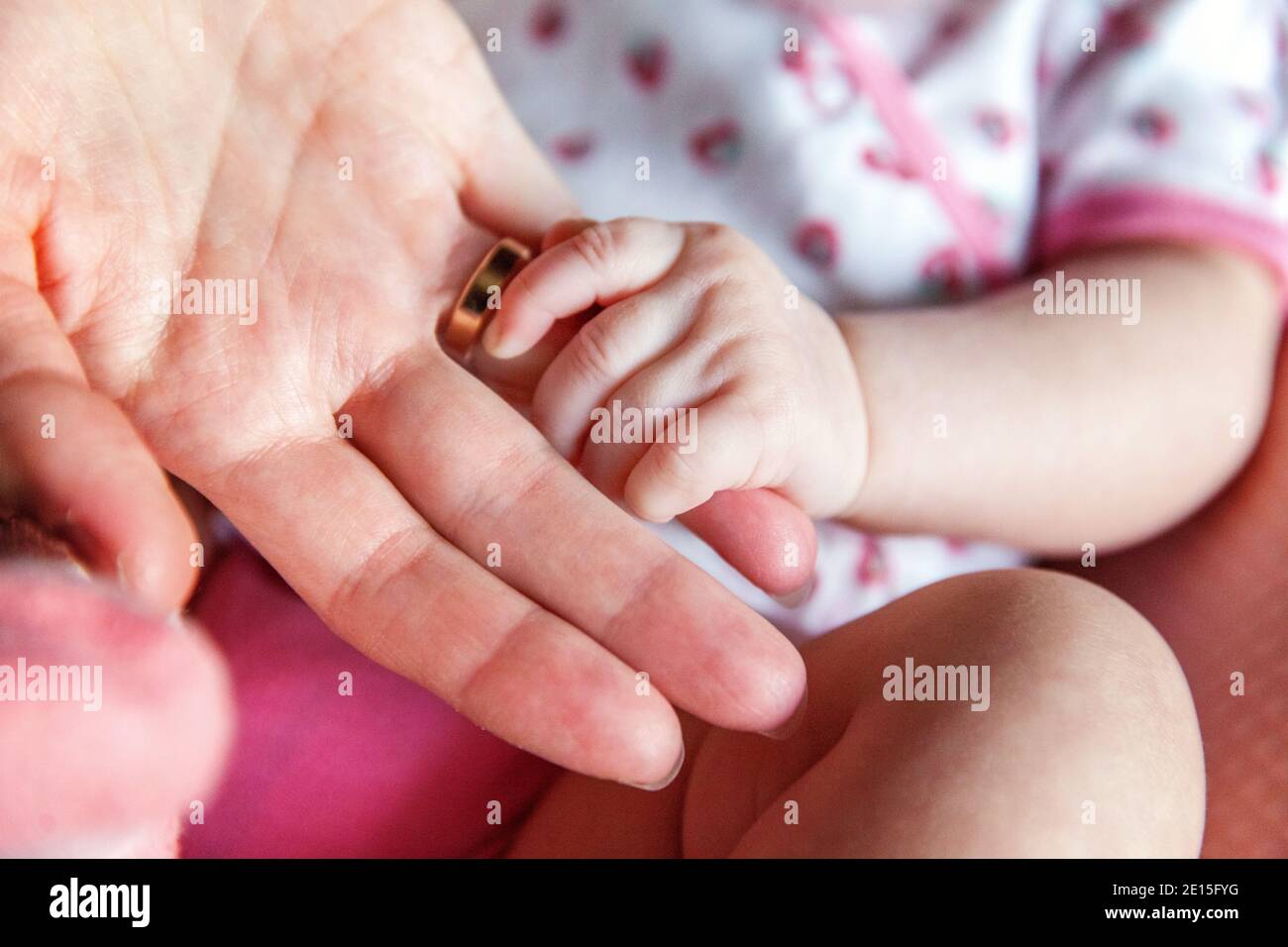 Little baby holding mother's hand. Tiny Newborn Baby's hand on female Shaped hands closeup. Mom
