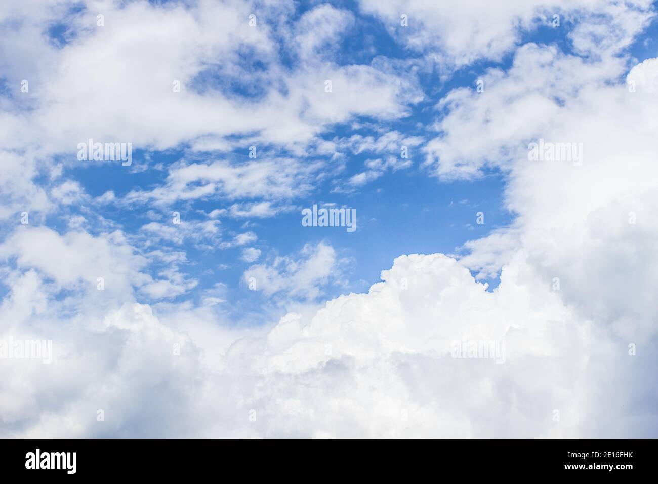 Blue sky background with white fluffy clouds framing copy space. Stock Photo