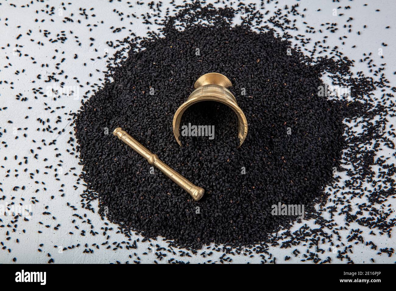 Nigella sativa seeds also known as black cumin, kalo jeera, kalonji and black caraway in iron scoop and mortar on white wooden background with copy sp Stock Photo