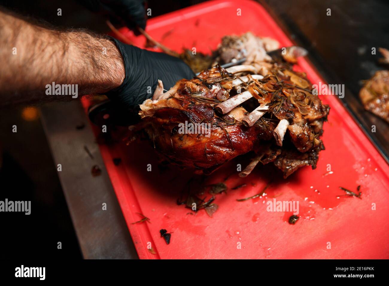 Chev cuts juicy cooked meat, separating the meat from the bone with a knife. Stock Photo