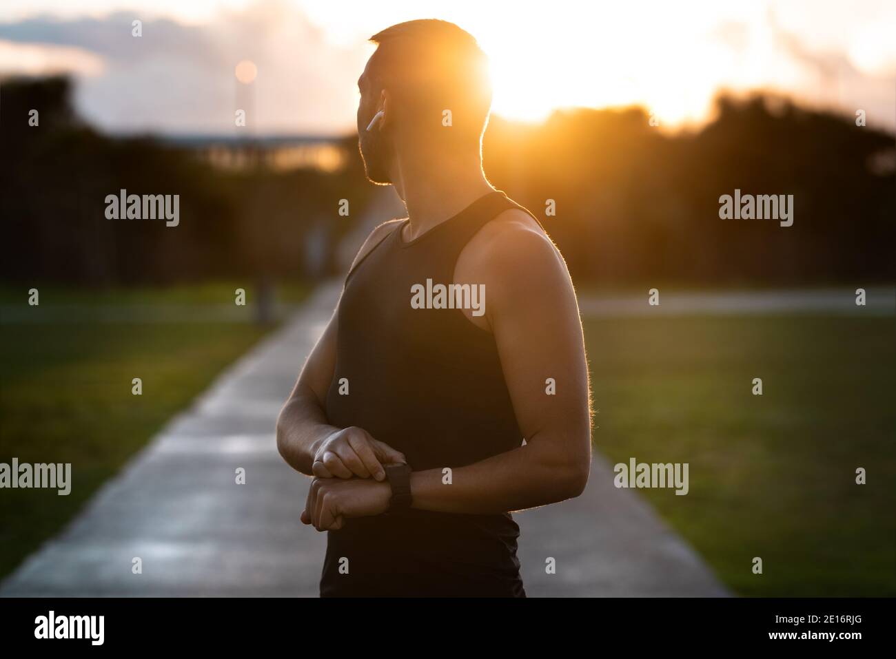 Athletic man running on sunset with smartwatch. and wireless headphones ...