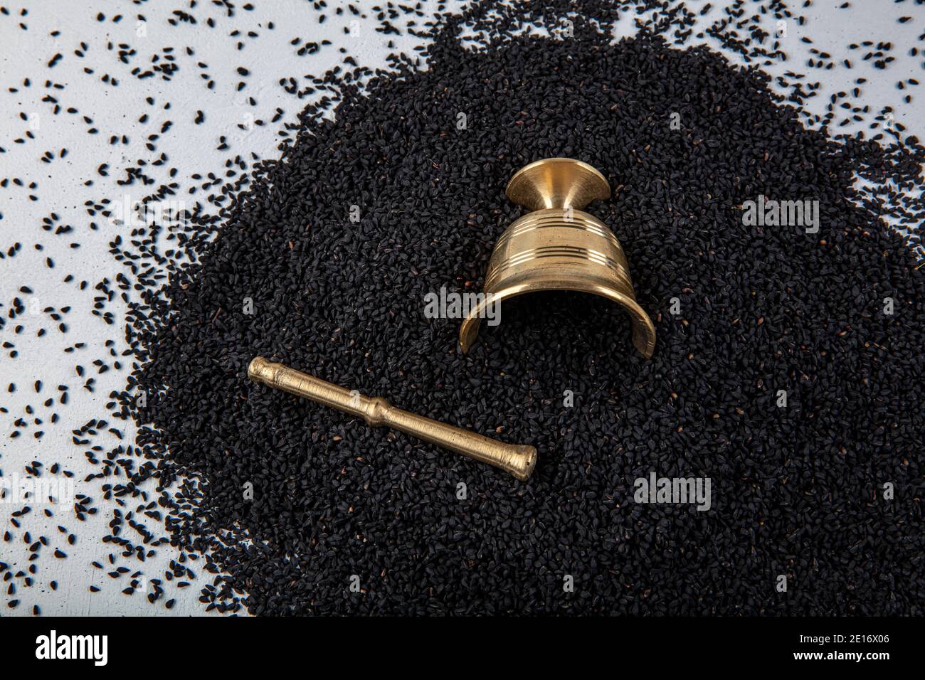 Nigella sativa seeds also known as black cumin, kalo jeera, kalonji and black caraway in iron scoop and mortar on white wooden background with copy sp Stock Photo