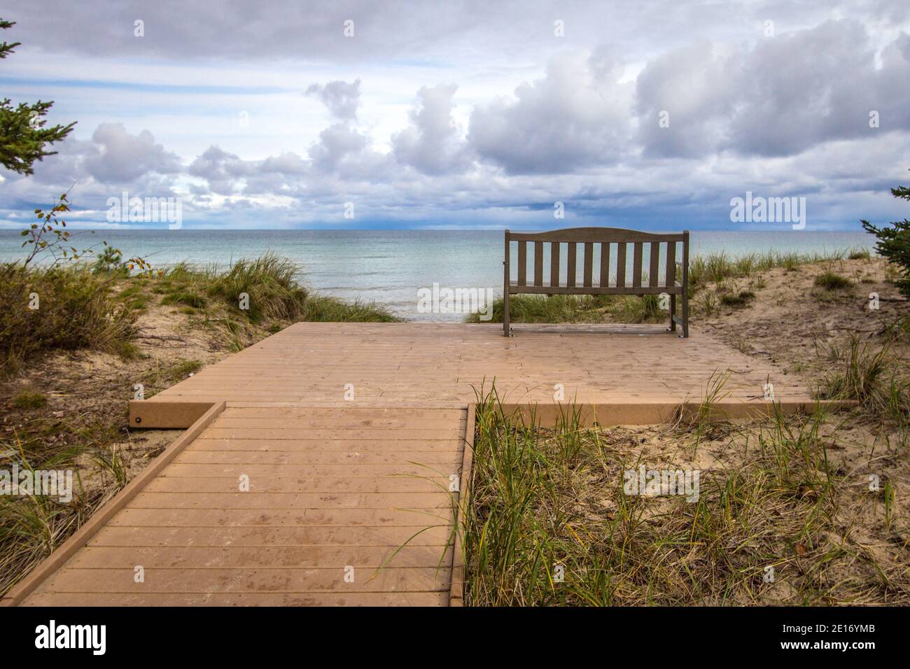 The End. Boardwalk path to an empty park bench overlooking a beautiful lake horizon on the coast of Lake Superior. Stock Photo