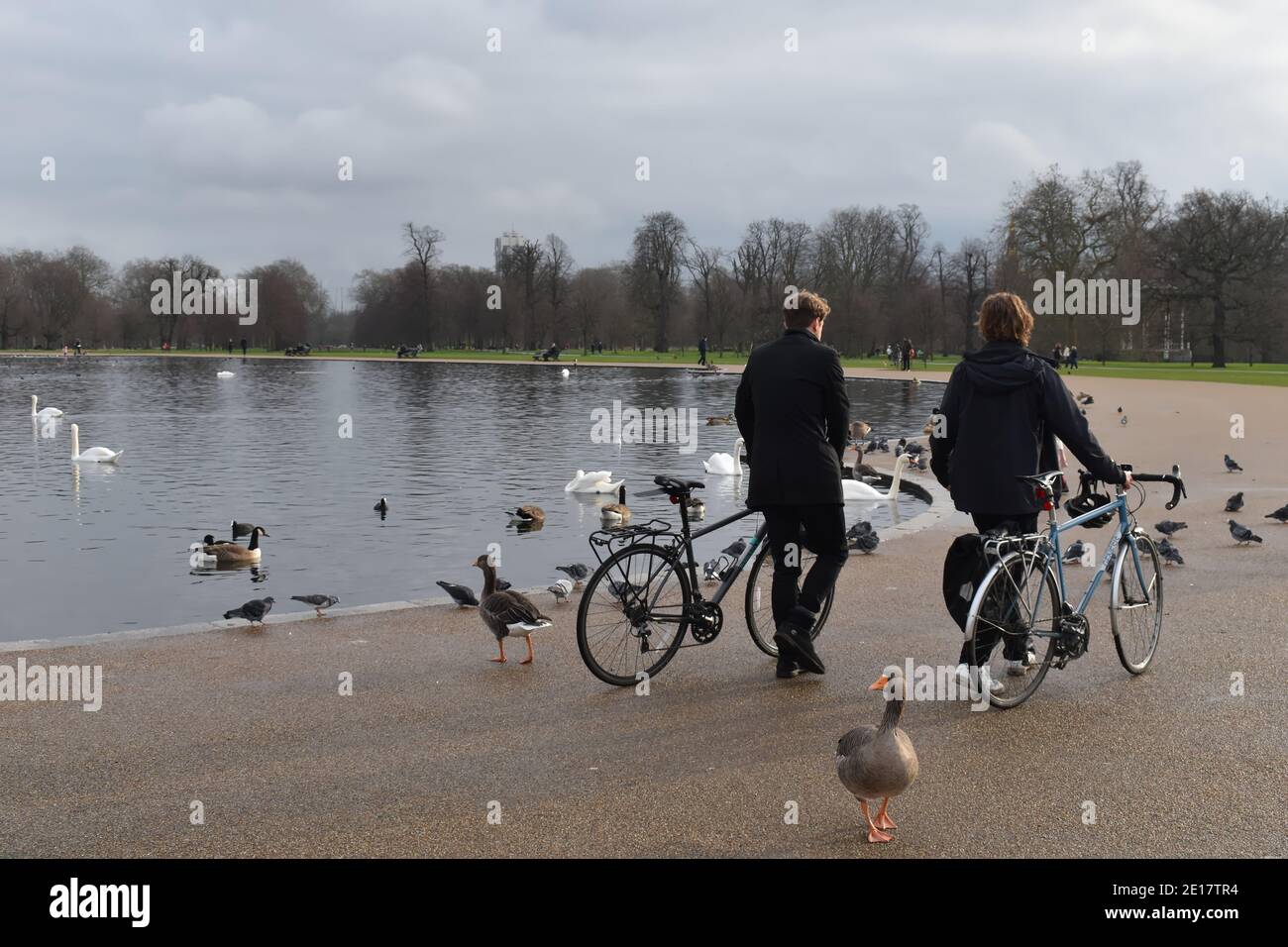 Lads pushing Genesis bikes by the round pond in Kensington gardens. It is an ornamental lake by Hyde park in London city in front of Kensington Palace Stock Photo