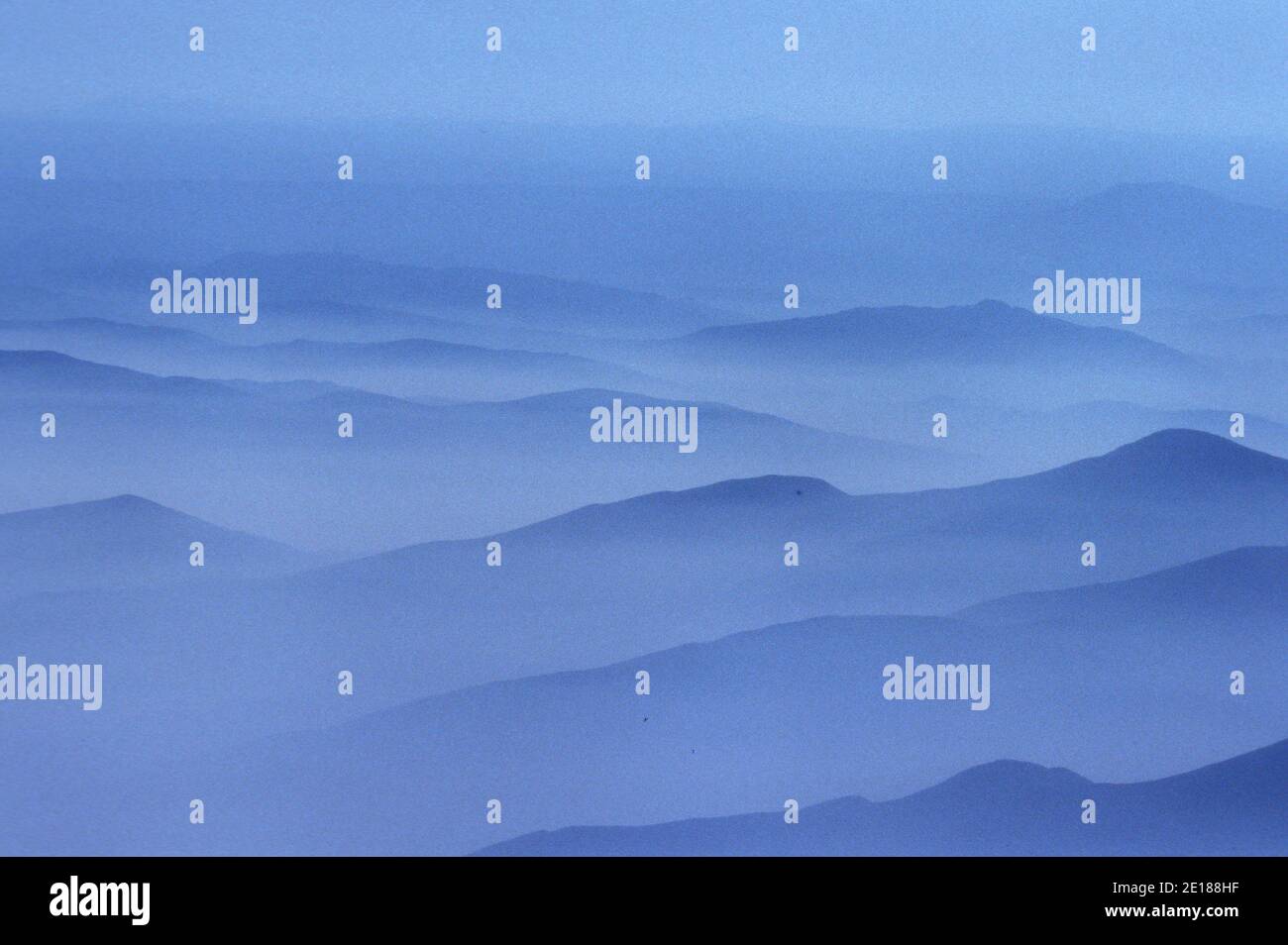 Misty white morning clouds with mountain ridges Stock Photo