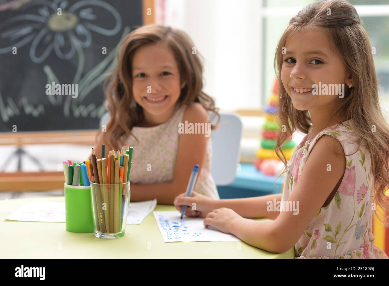 Two cute little girls drawing with pencils Stock Photo - Alamy