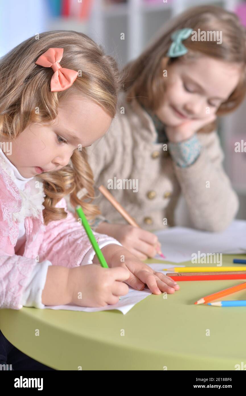 Portrait of two cute little girls drawing with pencils Stock Photo - Alamy
