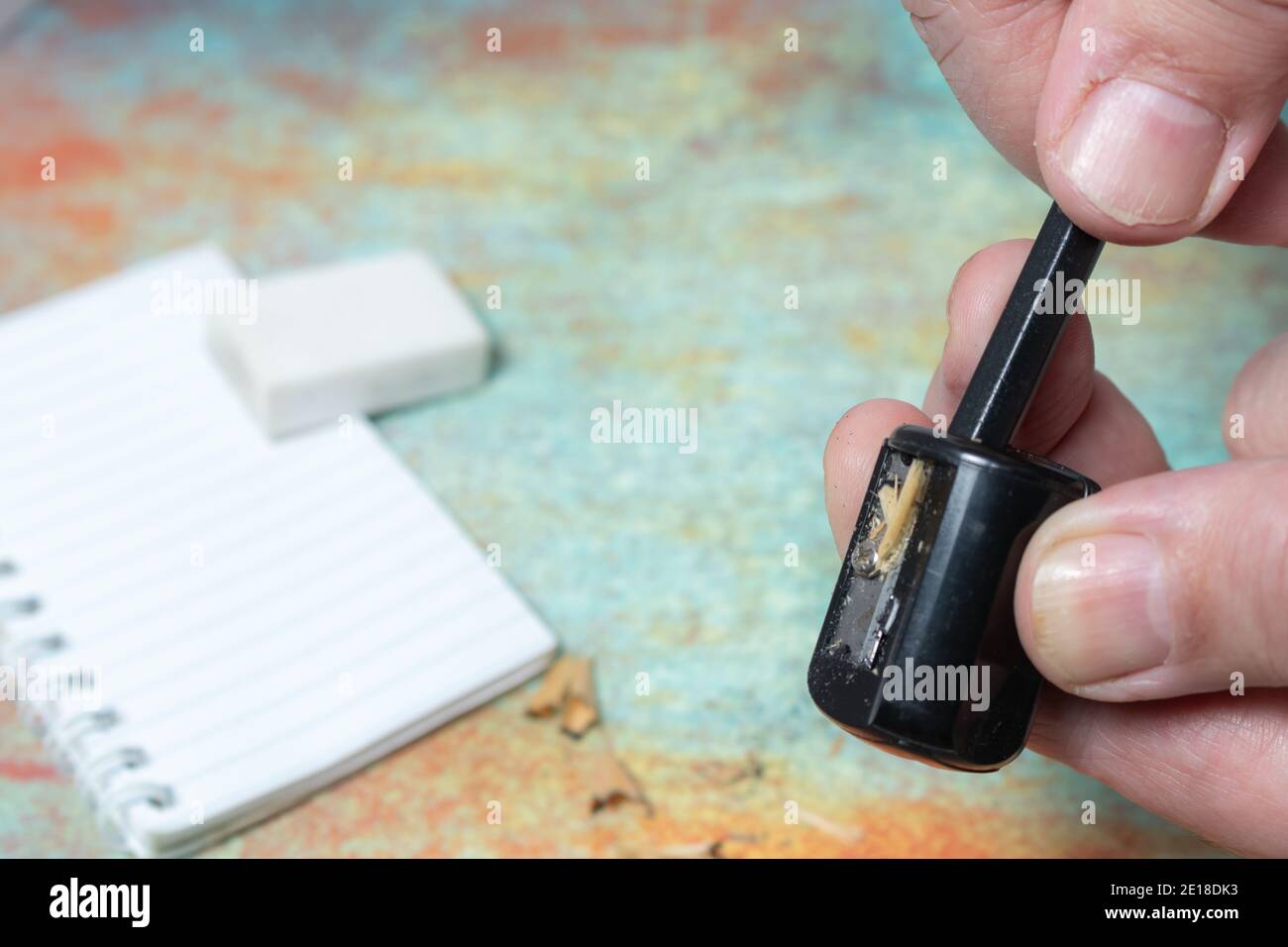Hands performing the action of sharpening a pencil with a standard pencil sharpener. Stock Photo