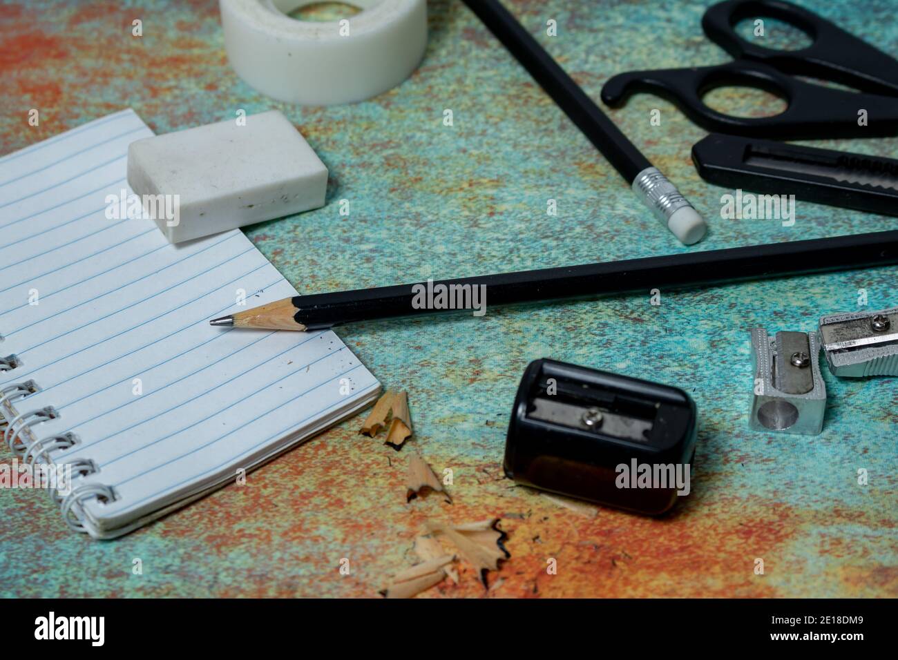 Small notebook, black pencil, eraser and other stationery on a rustic surface. Work items concept. Stock Photo