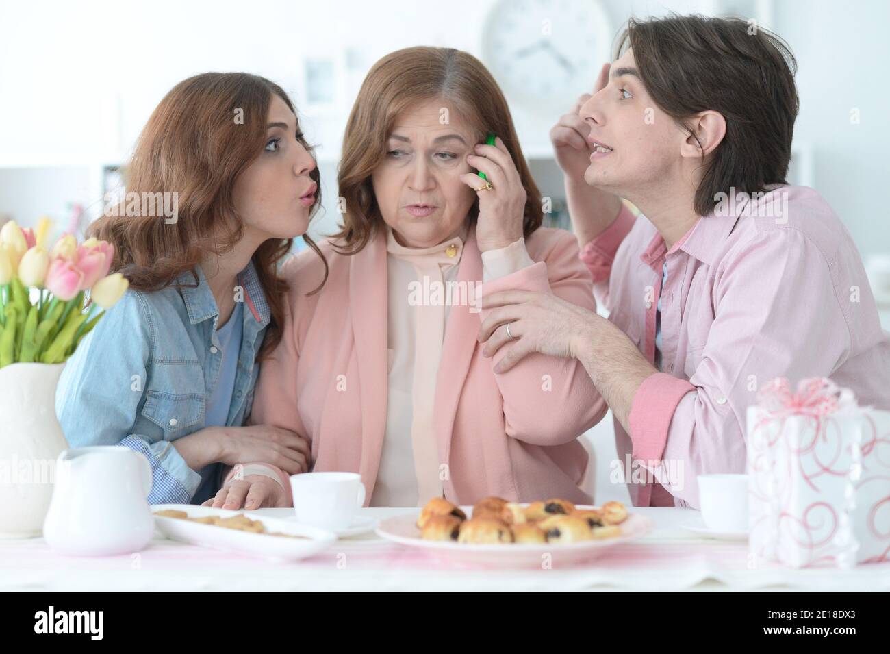 Adult children listening how their mature mother talking on phone Stock Photo