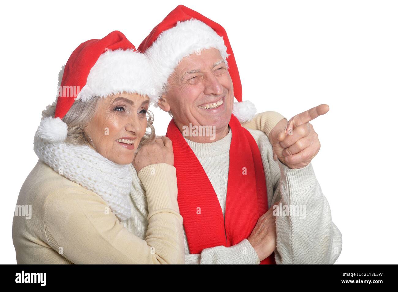 Portrait of happy senior couple in Santa hats pointing Stock Photo