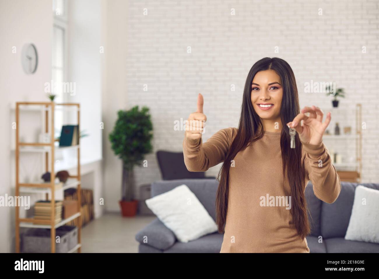 Happy young woman holding keys to her new apartment, smiling and giving ...