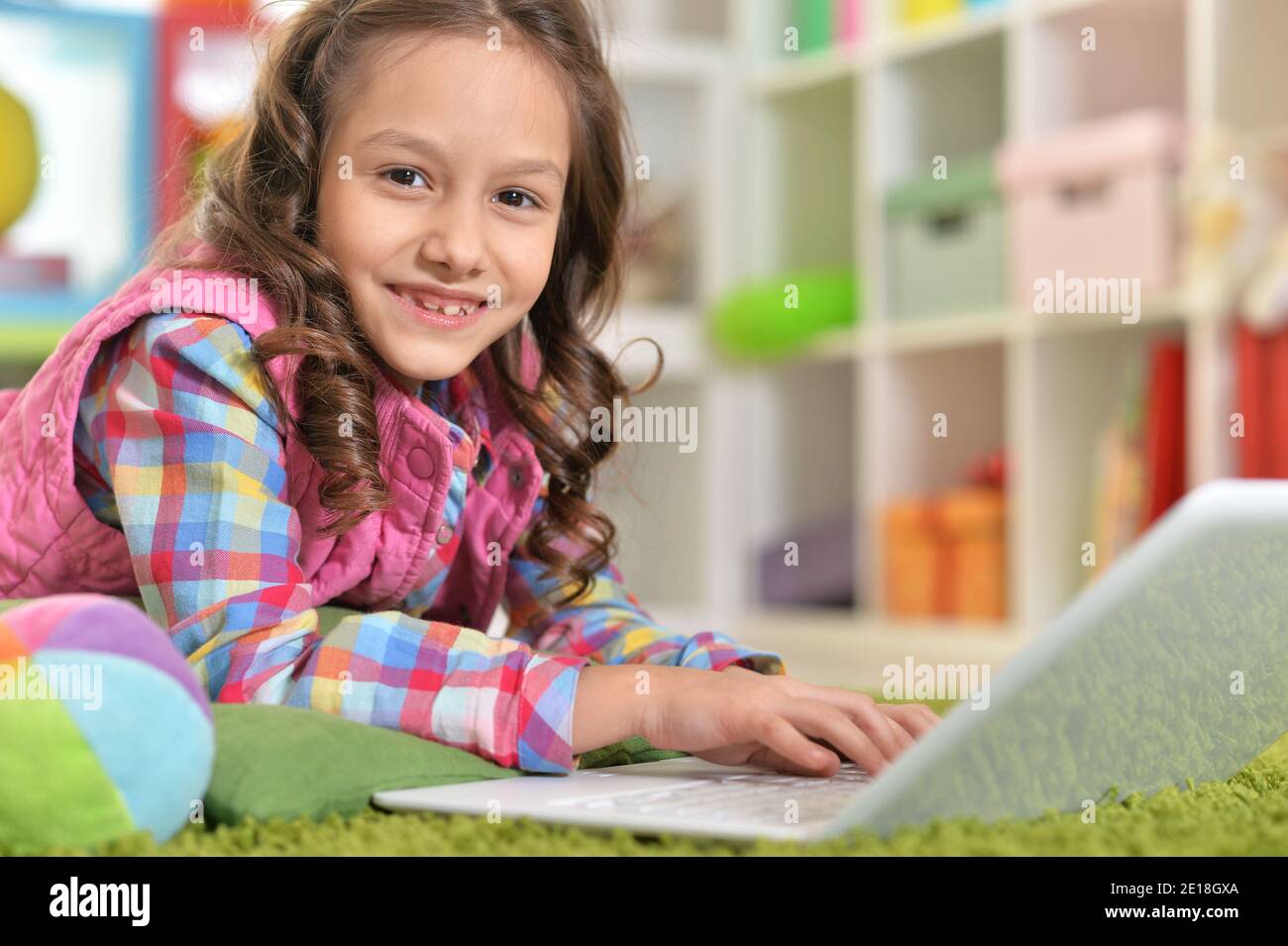 Cute girl using laptop while lying on green floor Stock Photo - Alamy