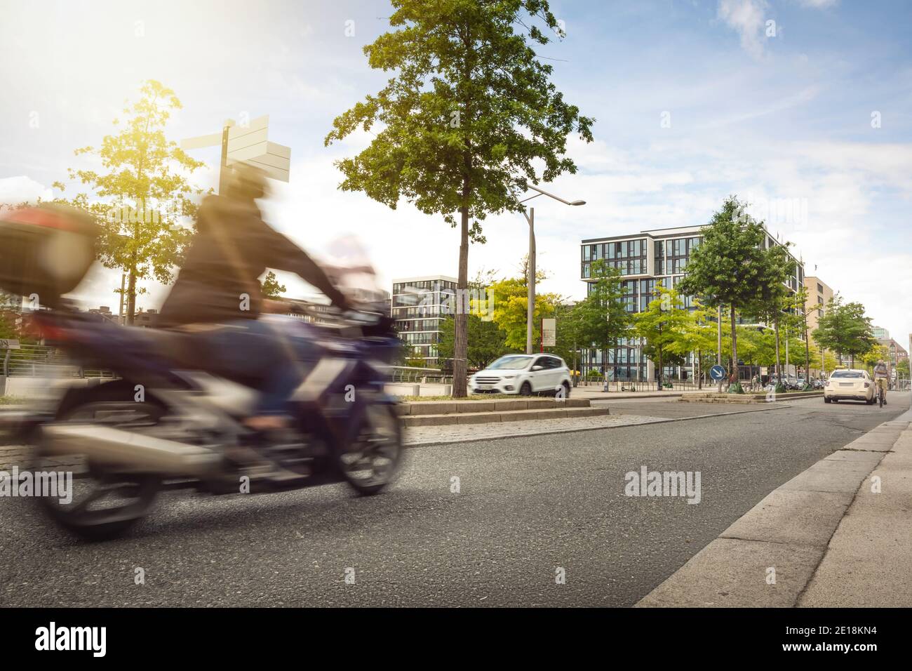 Urban street with a motorcycle driving by Stock Photo