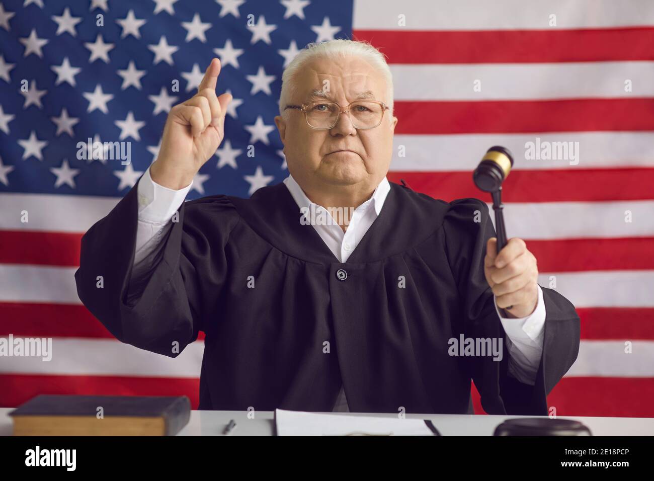 Serious American judge holding gavel and pronouncing his sentence in a court of law Stock Photo