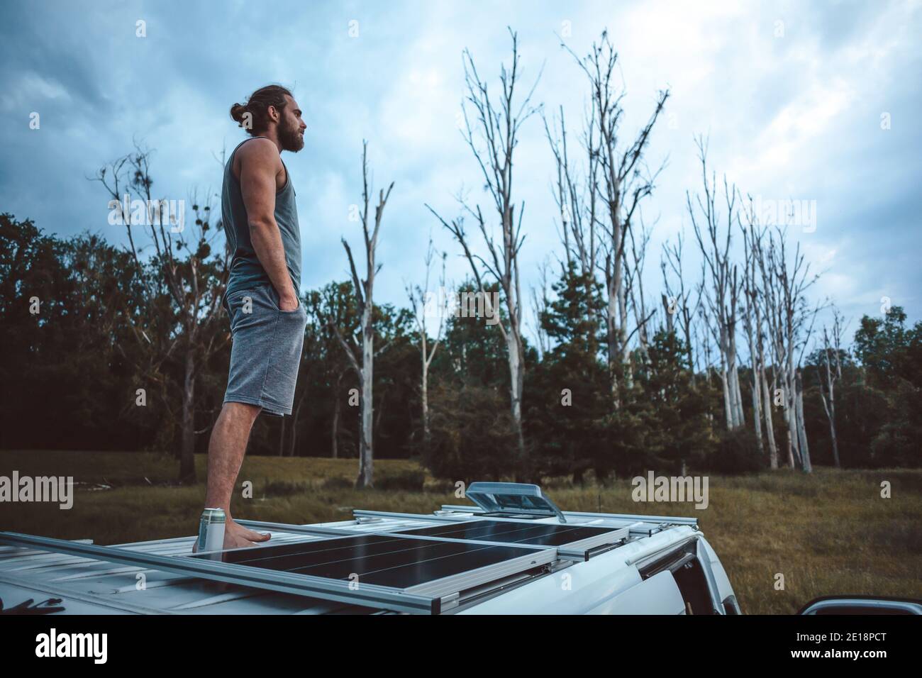 Man on top of his camper van in a moody scenery Stock Photo