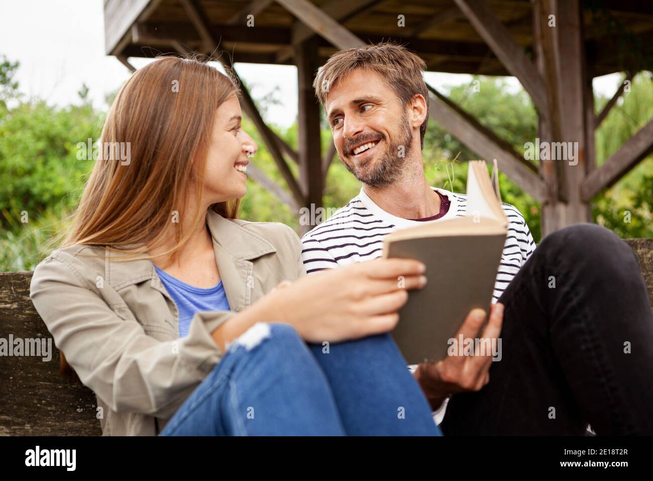 Couple sitting with book on bench Stock Photo