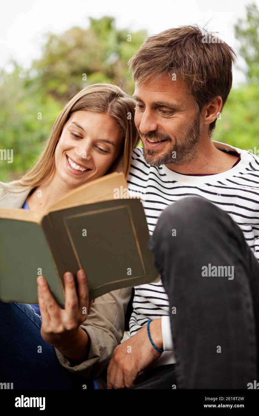 Couple reading book while sitting on bench Stock Photo