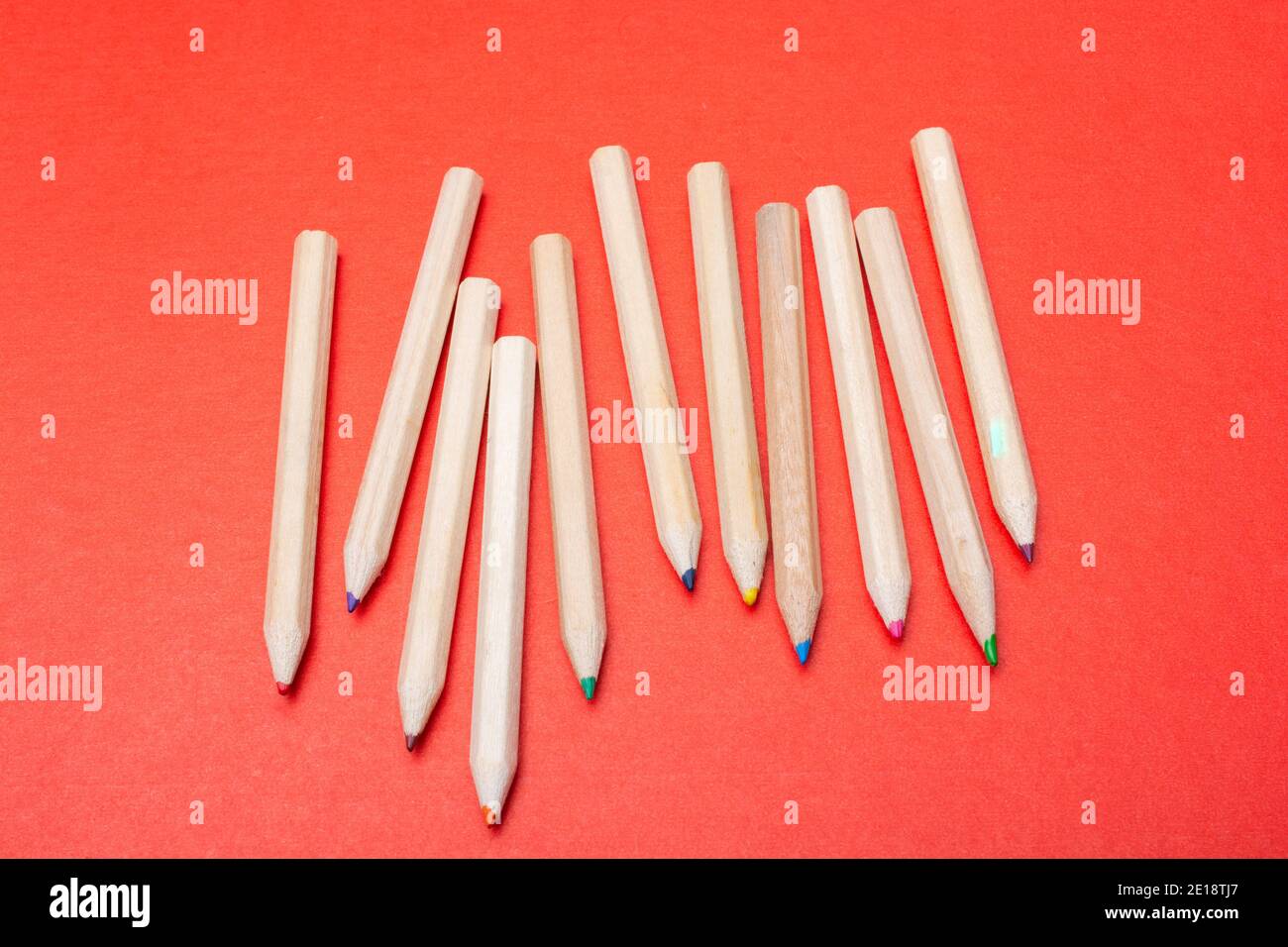 Colored pencils on red background. Many different colored pencils. Stock Photo