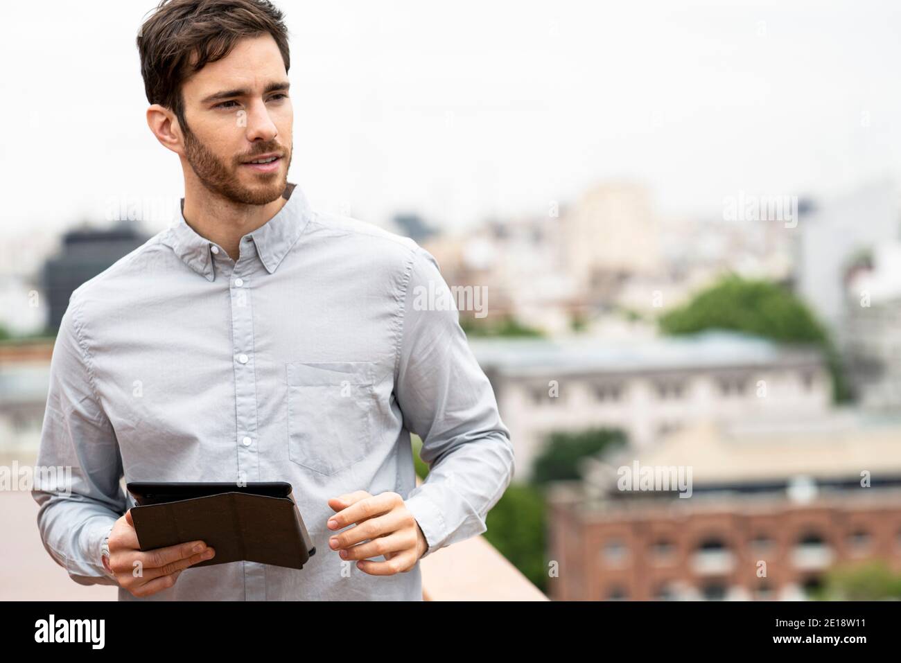 Young man standing outdoors with digital tablet Stock Photo