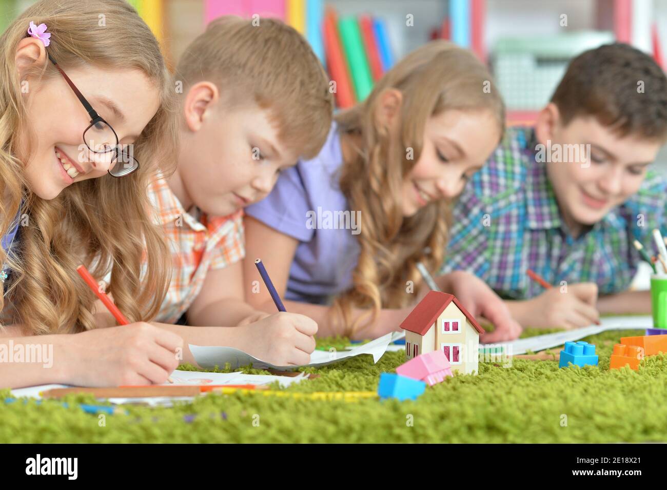 Children lying on floor drawing with pencils Stock Photo - Alamy