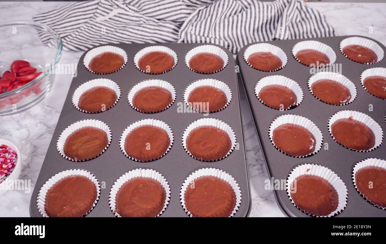 Step by step. Scooping cupcake batter into foil cupcake cups to bake red velvet cupcakes Stock
