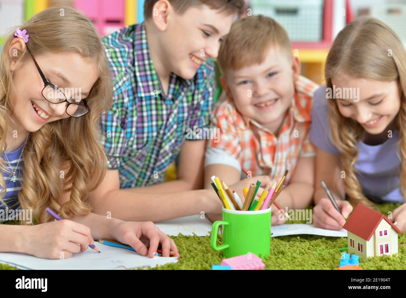 Children lying on floor drawing with pencils Stock Photo - Alamy