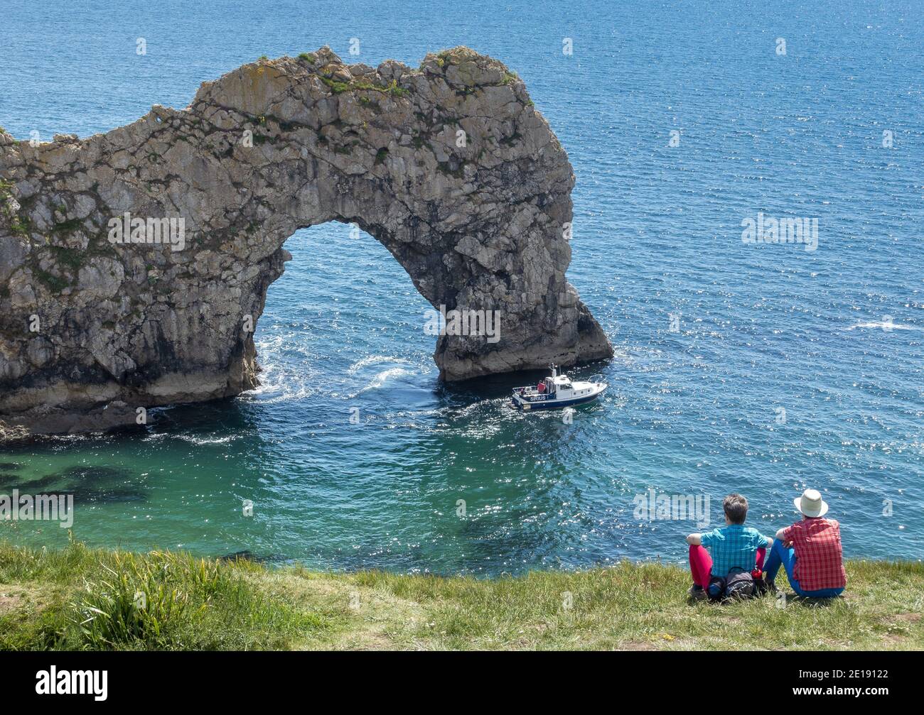 Couple wearing matching clothes relaxing in front of Durdle Door on the Jurassic Coast in Dorset, England, UK Stock Photo