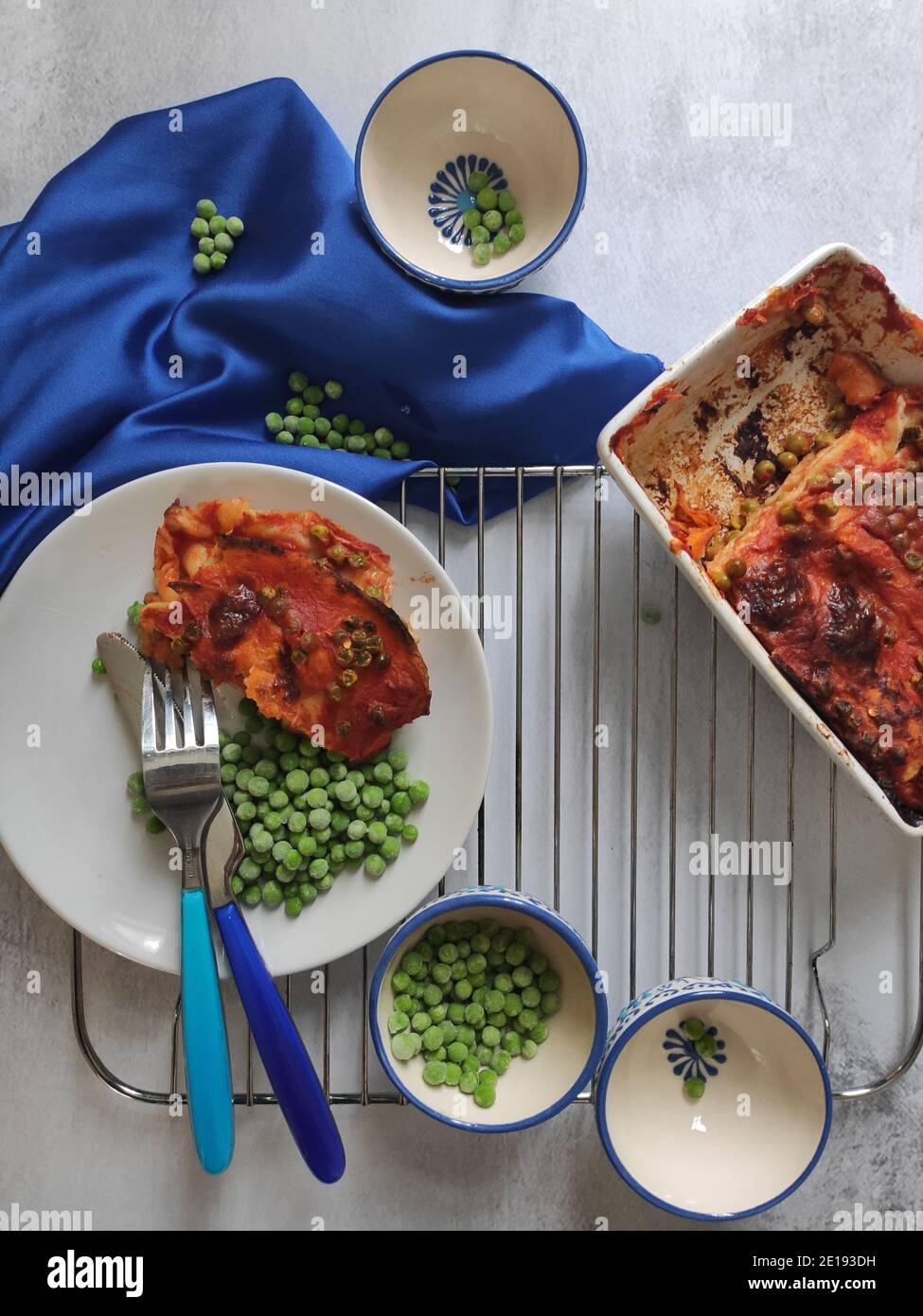 Green peas red lasagna in a blue dining set Stock Photo