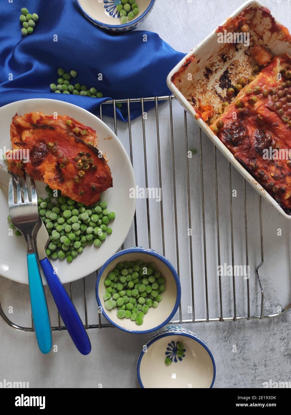 Green peas red lasagna in a blue dining set Stock Photo Alamy