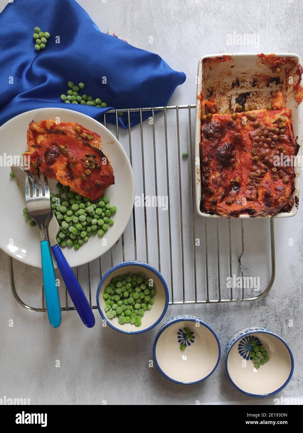 Green peas red lasagna in a blue dining set Stock Photo Alamy