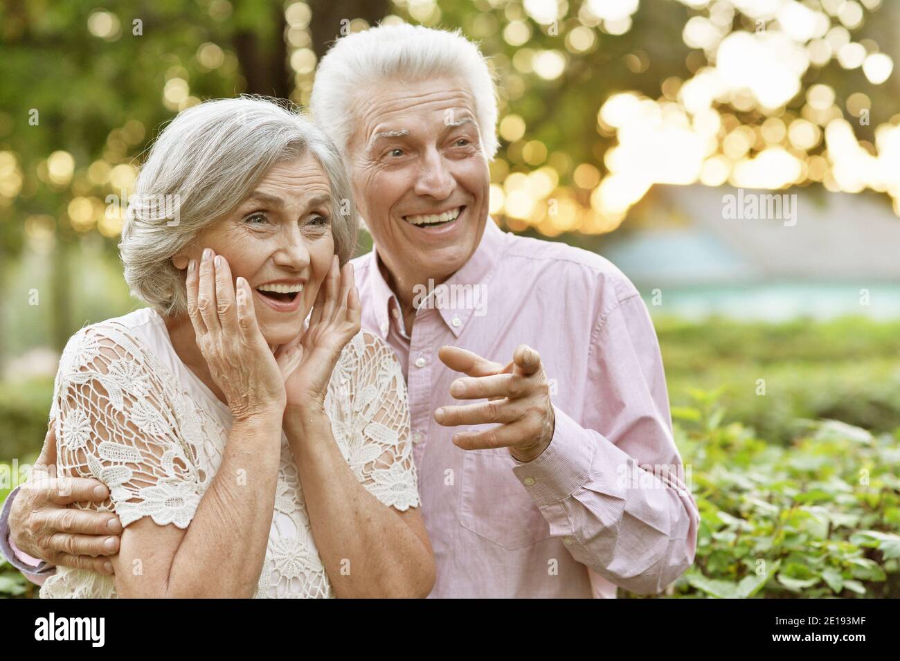 Beautiful senior couple in the park showing something Stock Photo - Alamy