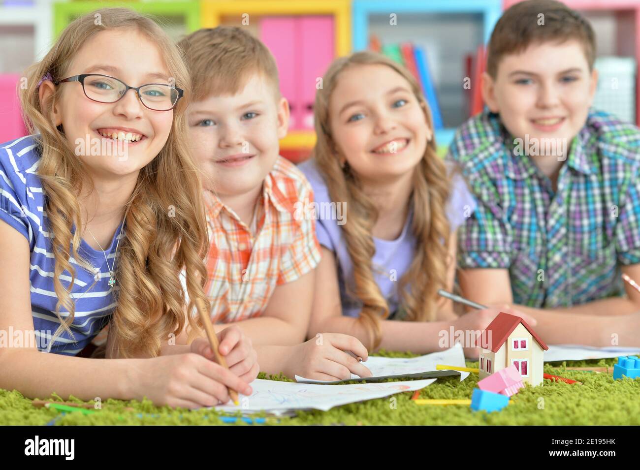 Children lying on floor drawing with pencils Stock Photo - Alamy
