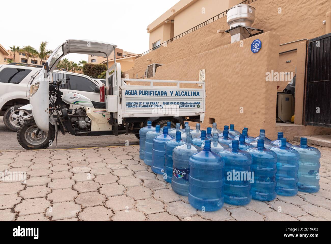 A large group of purified water bottles on the ground by a delivery truck. Stock Photo