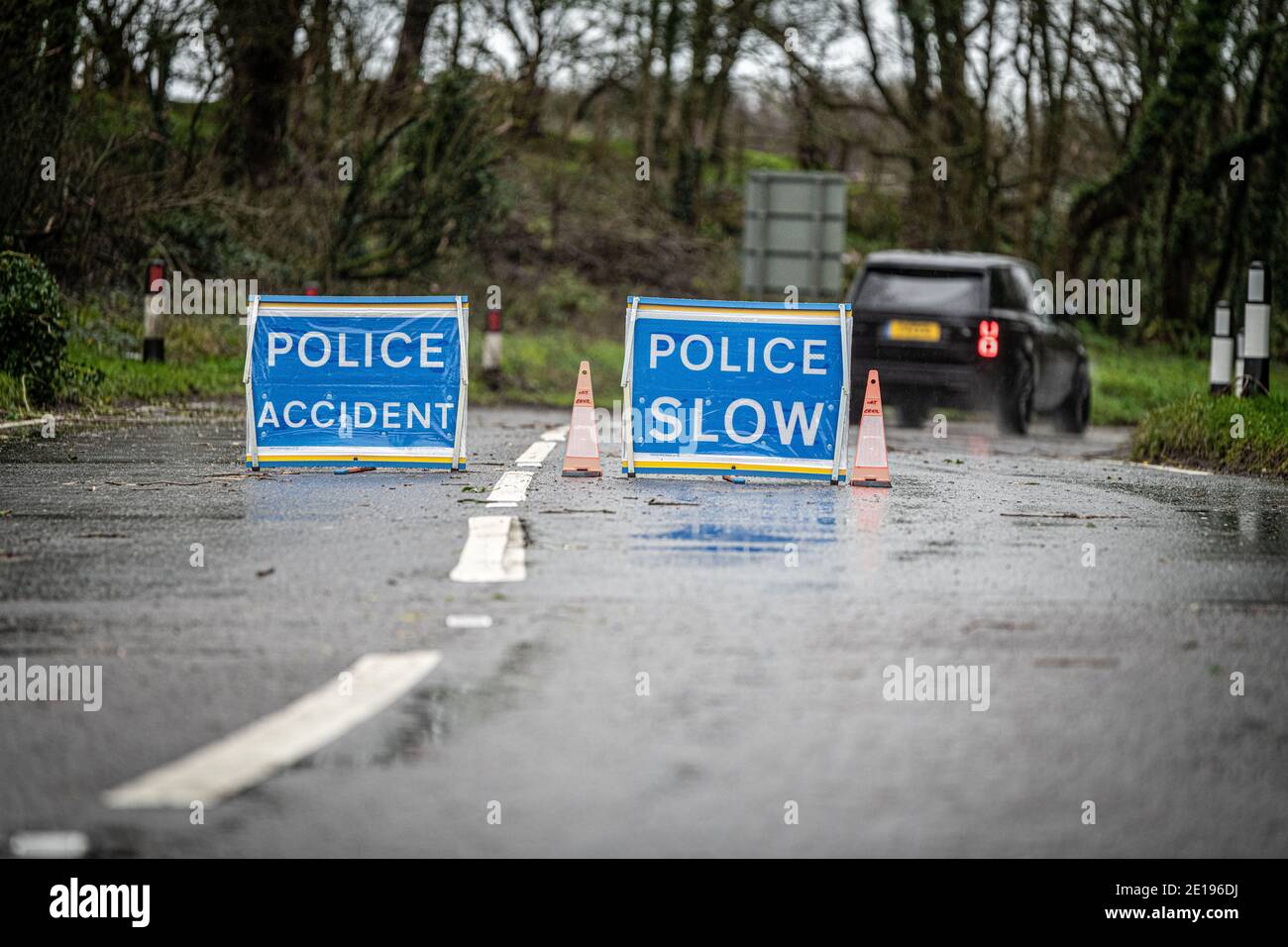 car driving past Police Acident signs on a wet road Stock Photo