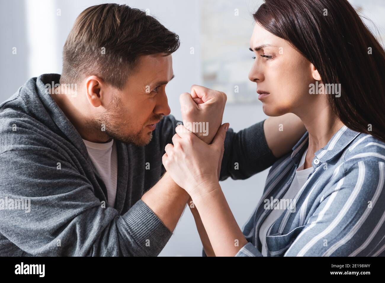 Abusive man showing fist to wife with bruise at home Stock Photo