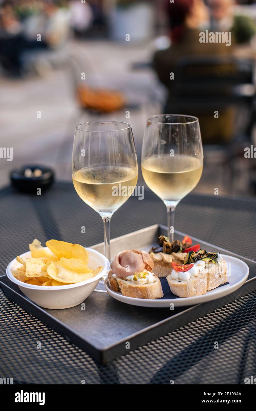 Venetian Cicchetti tartine bread and two glasses of white wine in a snack bar in Venice, Italy Stock Photo