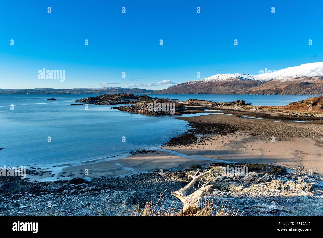 SCOTLAND WEST COAST HIGHLANDS KINTAIL SANDAIG BAY ISLANDS BEACH THE MOUTH OF THE RIVER AND SNOW COVERED MOUNTAINS OF SKYE IN WINTER Stock Photo