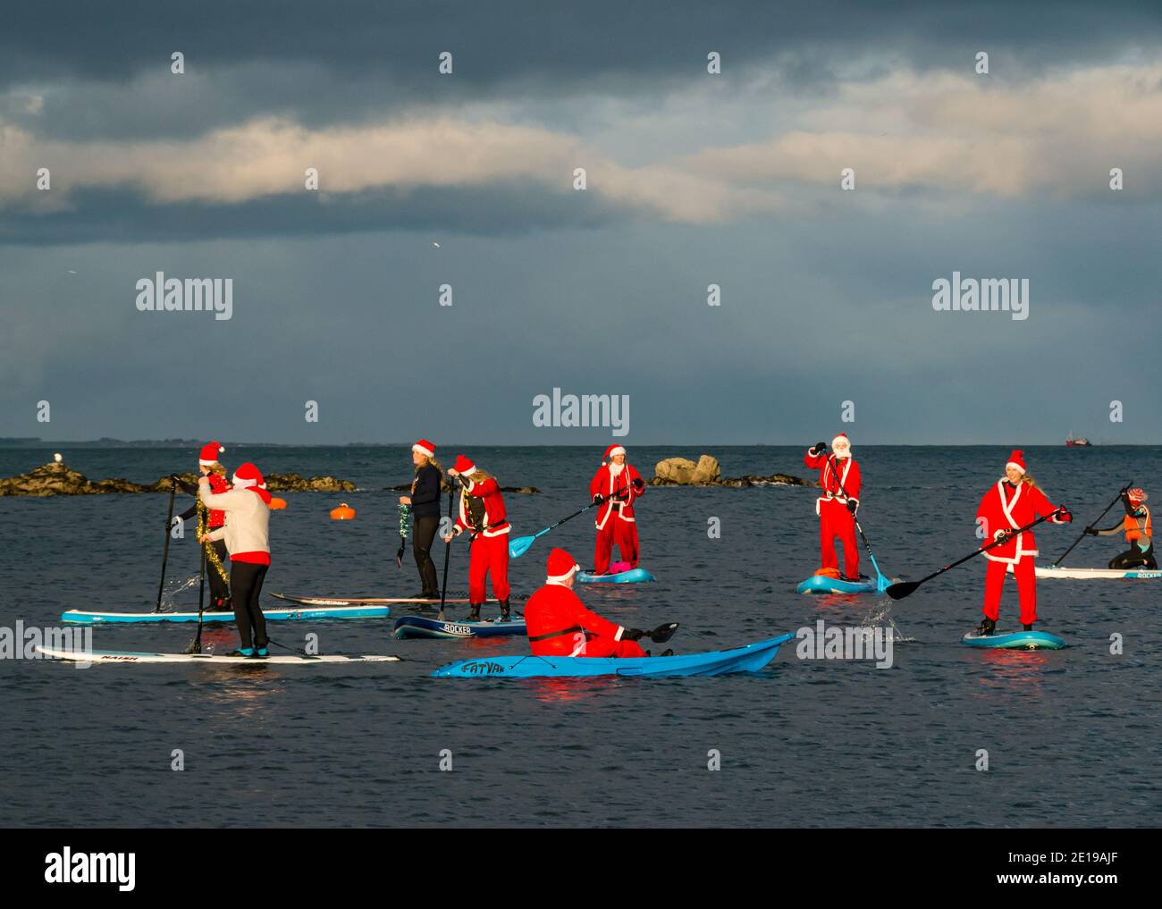 Community charity event: paddle boarders in Santa costumes, North Berwick, East Lothian, Scotland, UK Stock Photo
