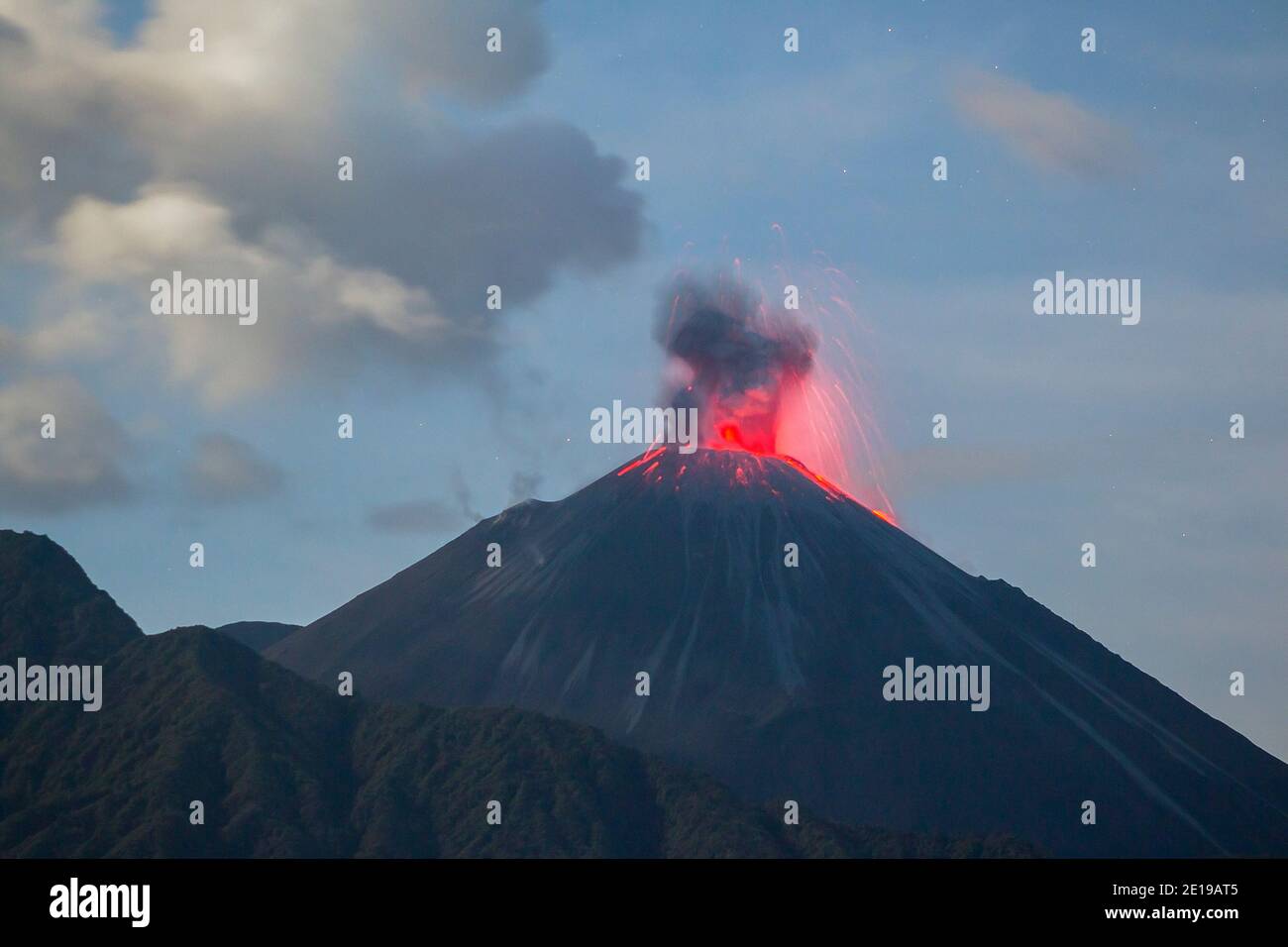 Reventador Volcano, Ecuador erupting at night, November 2015. Red hot rocks and gas are thrown out of the crater. Reventador rises out of tropical rai Stock Photo