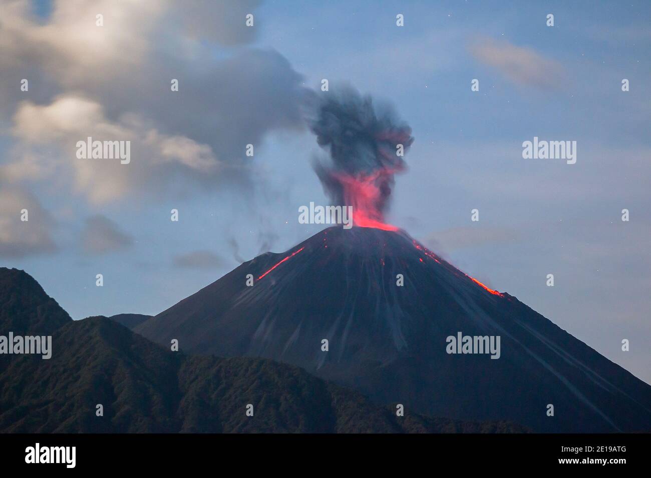 Reventador Volcano, Ecuador erupting at night, November 2015. Red hot rocks and gas are thrown out of the crater. Reventador rises out of tropical rai Stock Photo