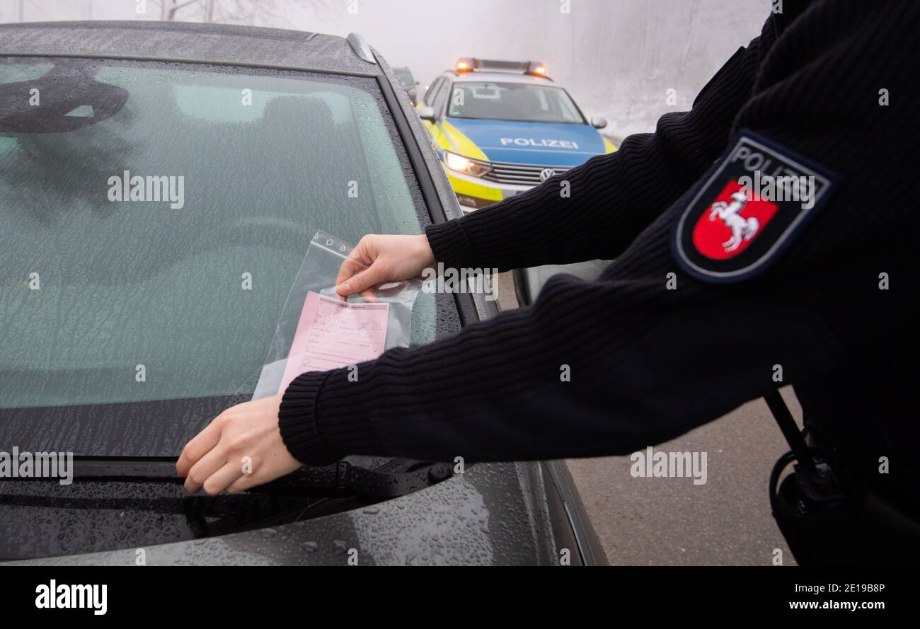 Nienstedt, Germany. 05th Jan, 2021. A policewoman hangs a parking ticket on an irregularly parked vehicle on highway 401 at the Nienstedter Pass in the Deister. The Hanover police and the public order office report overcrowded parking spaces in the snow-covered Deister. Offences of wrong parkers are punished. Credit: Julian Stratenschulte/dpa/Alamy Live News Stock Photo